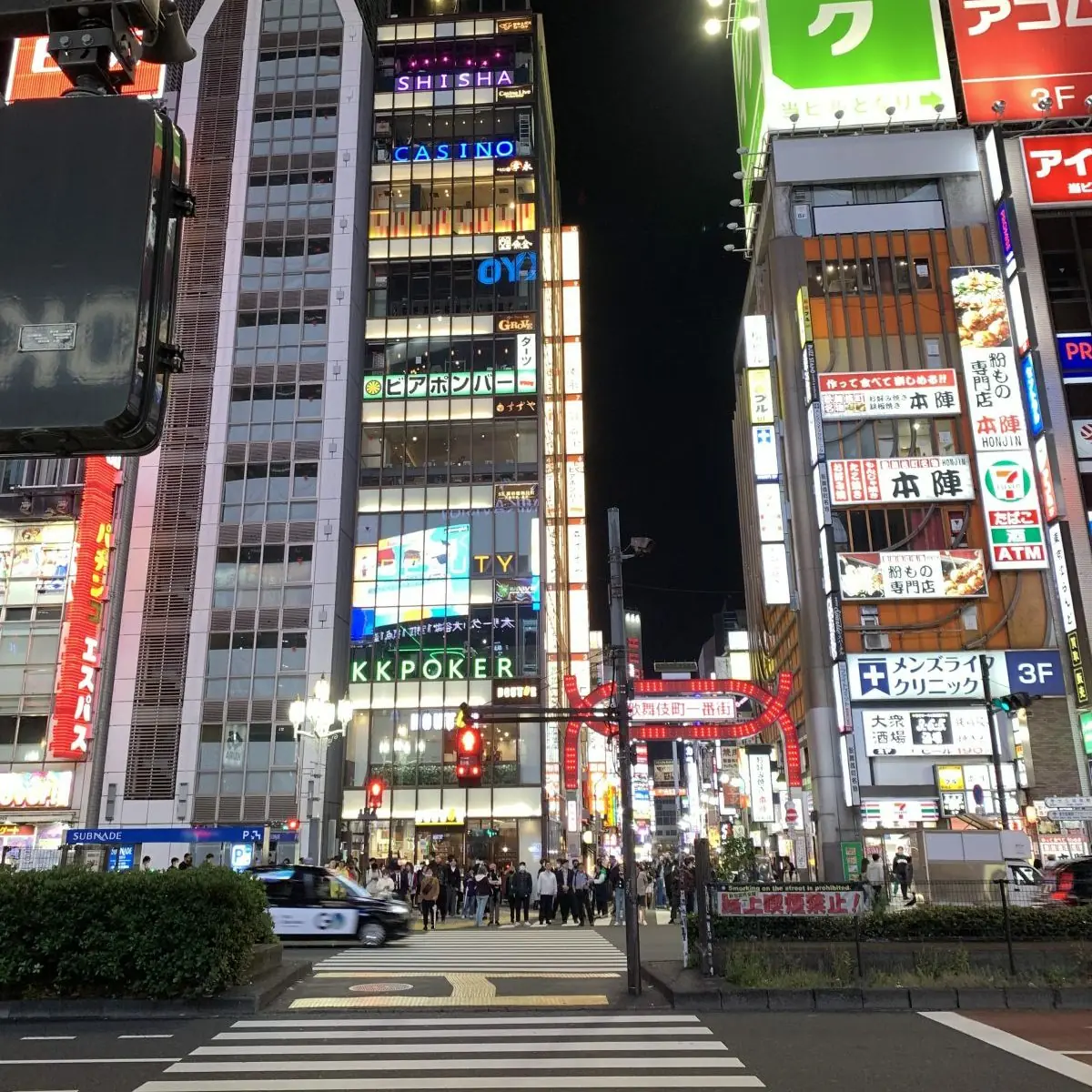 Neon-lit Tokyo side street at night, lined with izakaya lanterns and signs