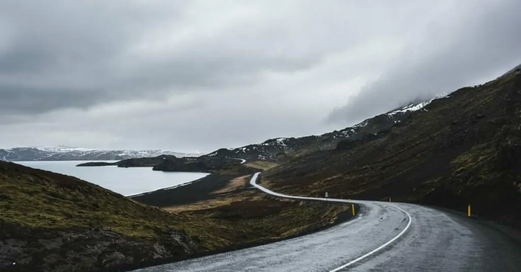 A winding coastal road beneath cloud-covered mountains in Iceland