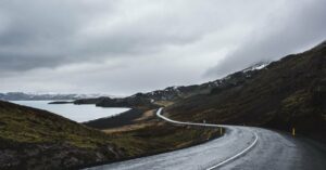 A winding coastal road beneath cloud-covered mountains in Iceland