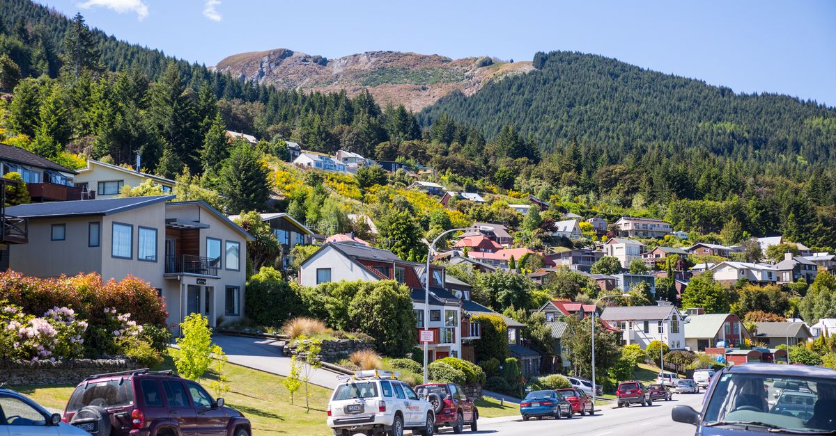 Residential street in Queenstown with parked cars and mountain views